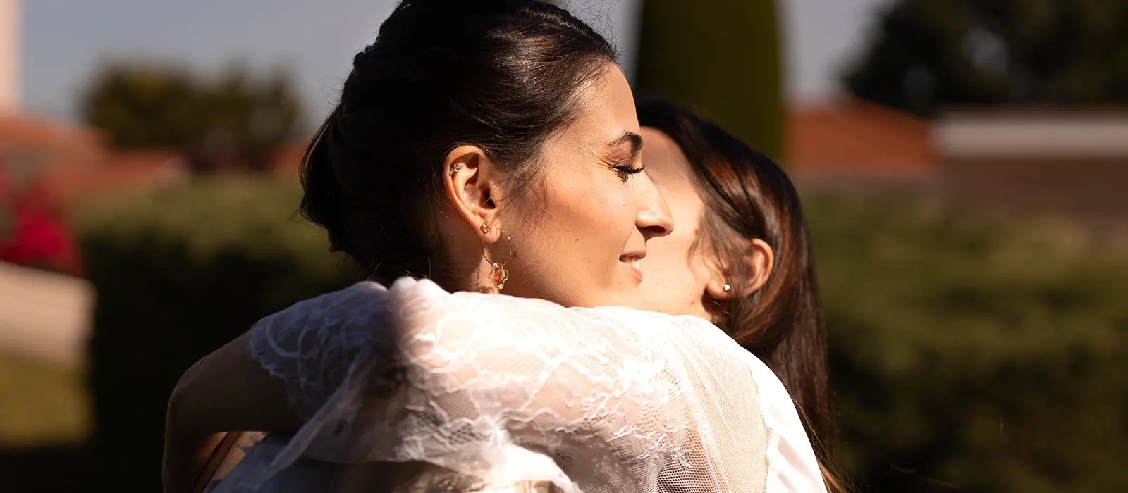 Étreinte chaleureuse et émouvante entre la mariée et une proche sous une belle lumière de fin de journée