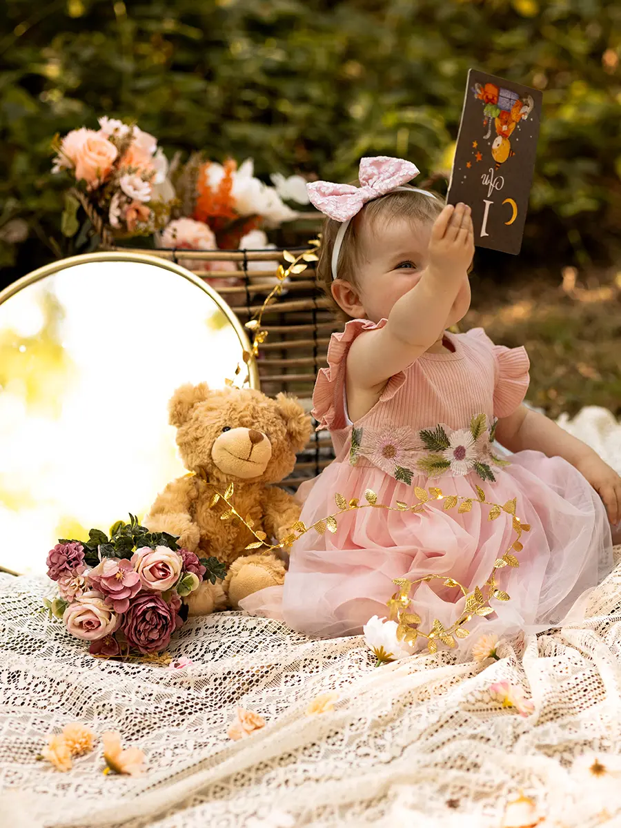 Portrait en extérieur d'un bébé fille fêtant son premier anniversaire avec un ours en peluche