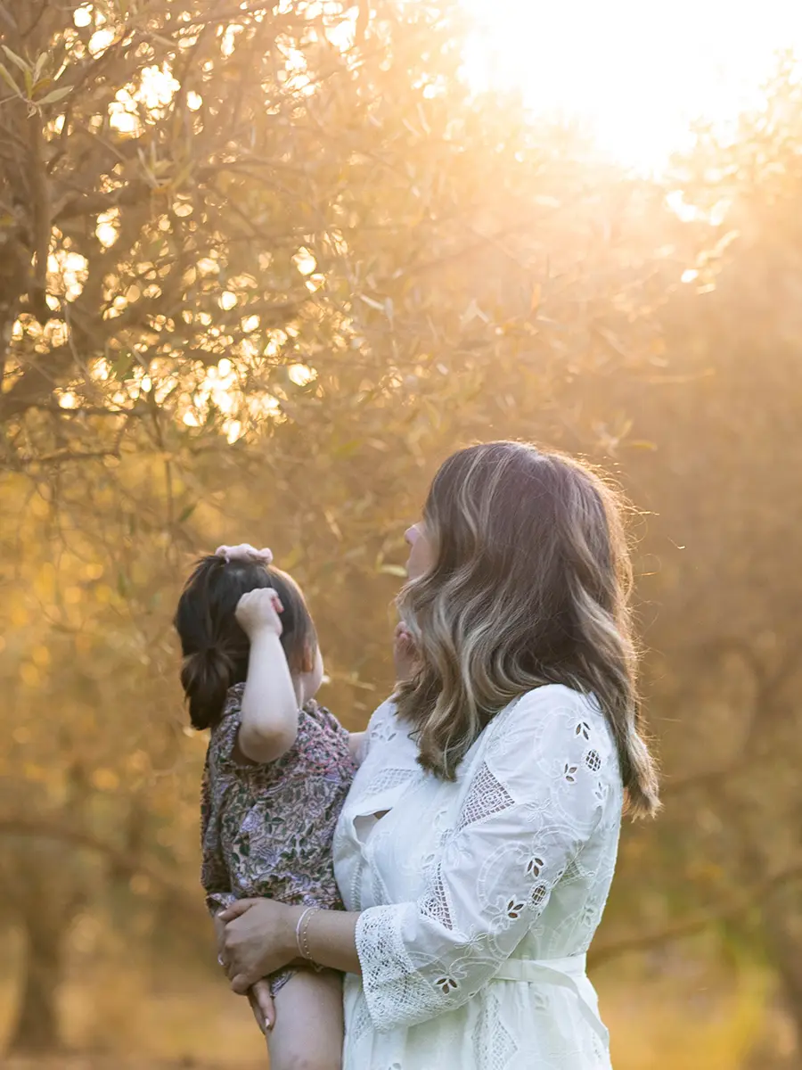 Une mère portant sa petite fille dans les bras sous la lumière dorée du coucher de soleil