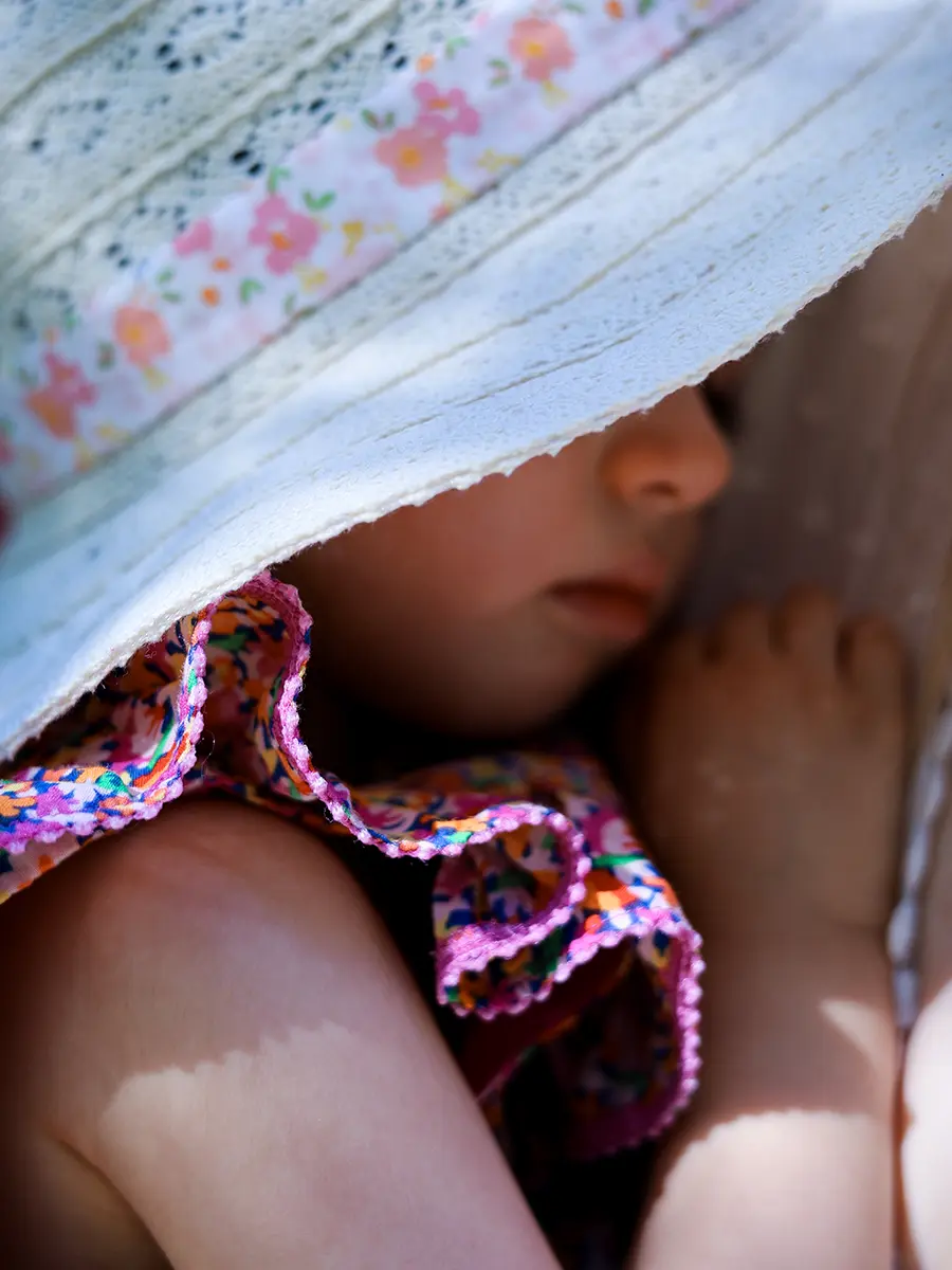 Gros plan sur le visage d'une petite fille endormie cachée sous un chapeau de paille estival