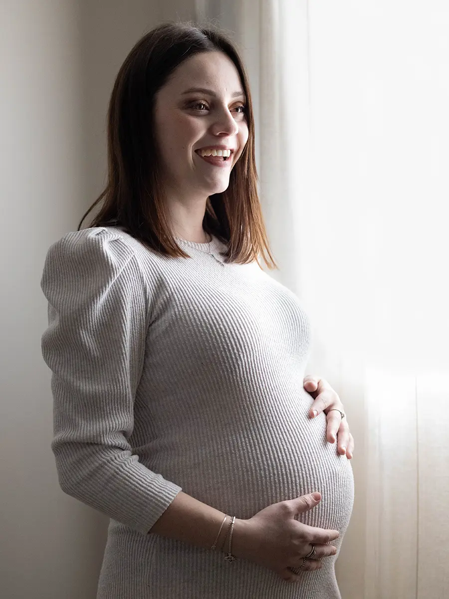 Portrait lumineux d'une future maman souriante tenant son ventre rond en studio