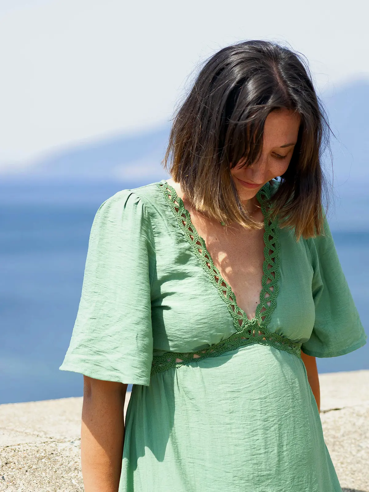 Portrait de Justine Celle, photographe, souriant naturellement dans une robe verte au bord de la mer